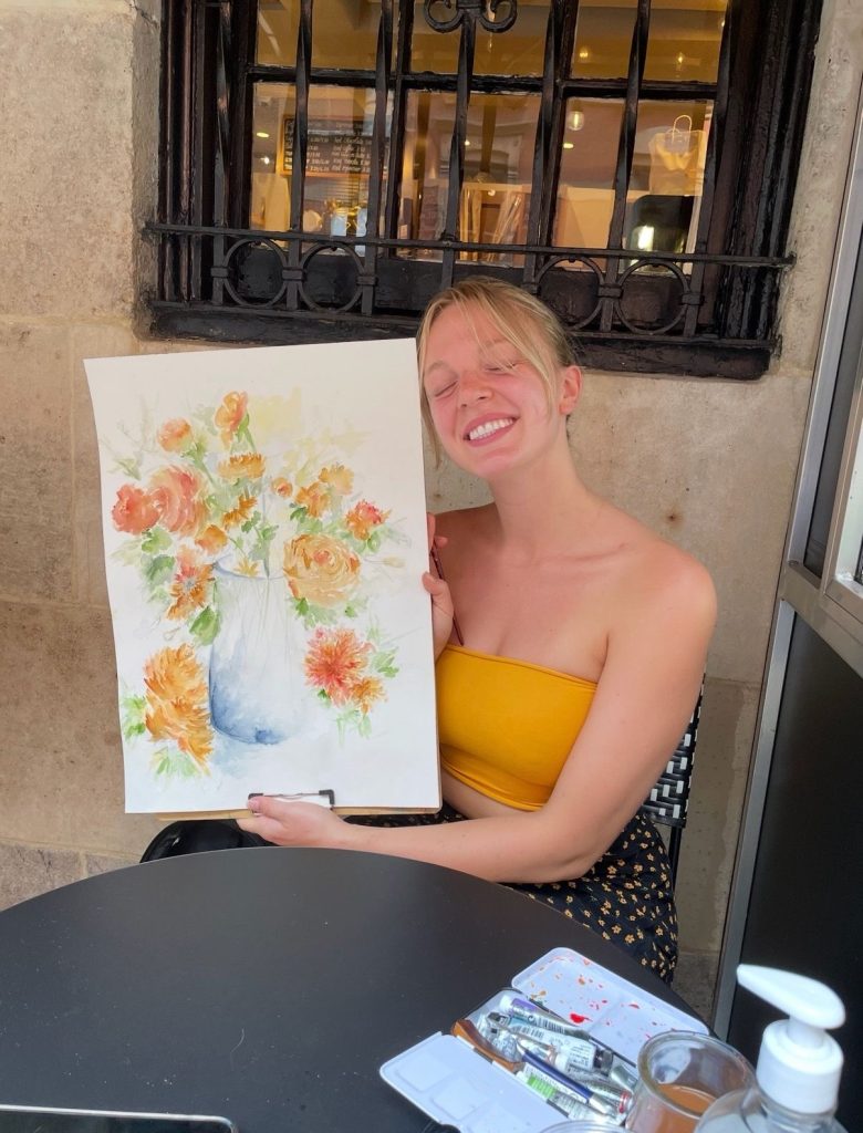 Emma Larson holding painting and smiling